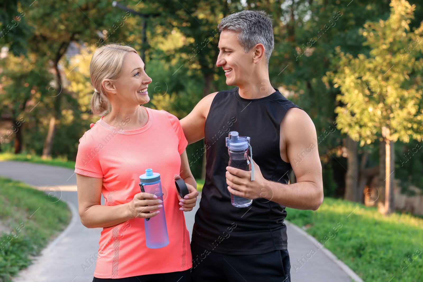 Photo of Happy couple with bottles of water in park