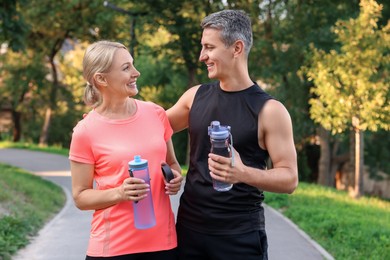 Happy couple with bottles of water in park