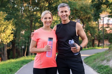 Happy couple with bottles of water in park