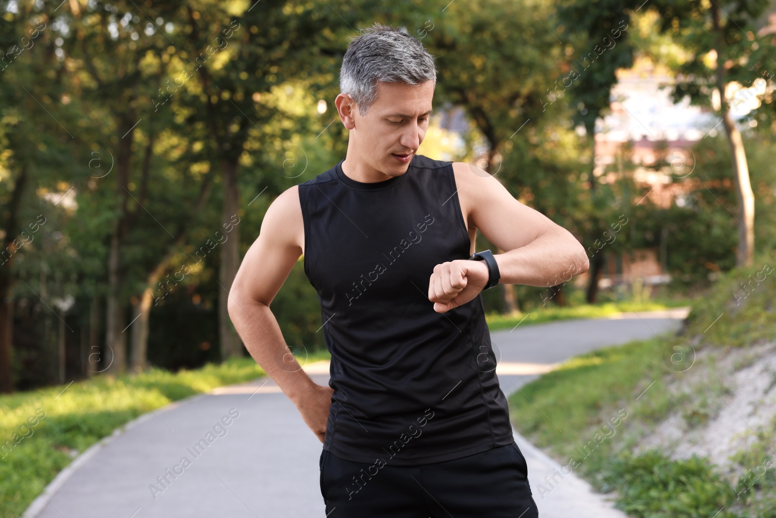 Photo of Man in sportswear checking time in park