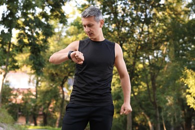 Photo of Man in sportswear checking time in park