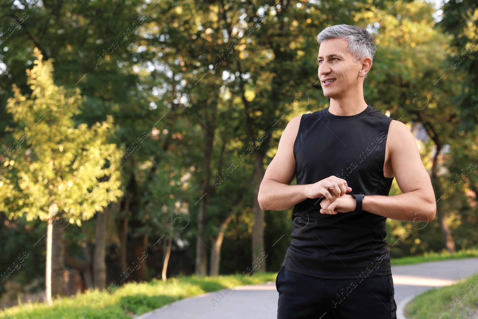 Photo of Man in sportswear checking time in park, space for text