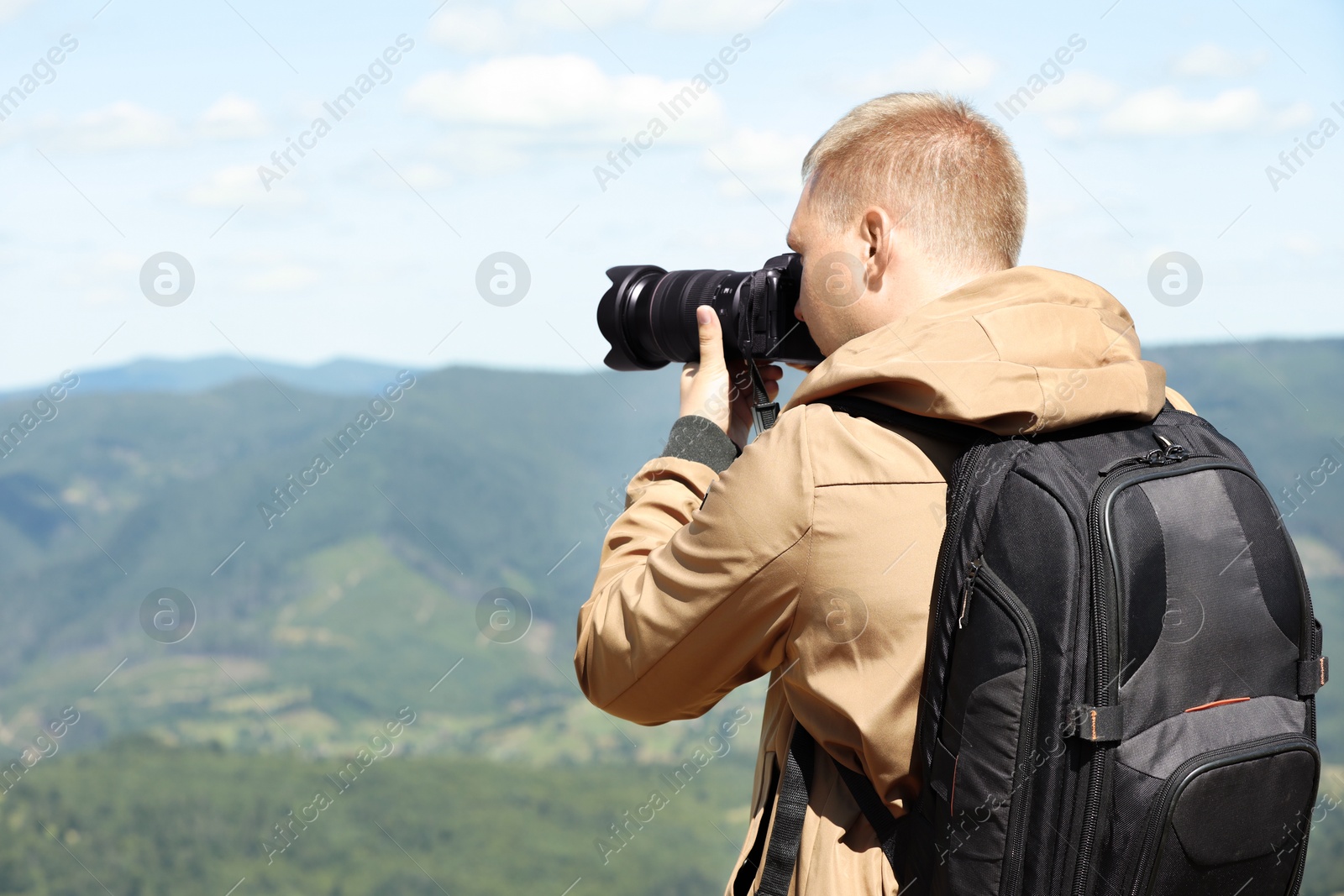 Photo of Photographer with backpack and camera taking picture of beautiful mountains, space for text