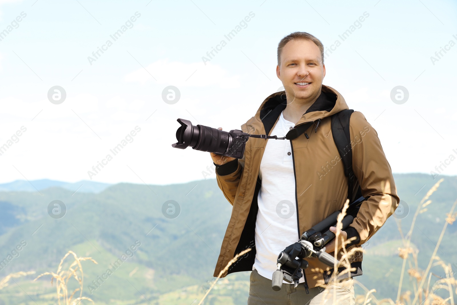 Photo of Photographer with camera and other professional equipment in mountains, space for text