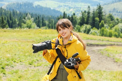 Photographer with backpack, camera and other professional equipment in mountains