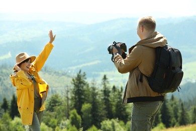 Photographer with backpack and camera taking picture of model in beautiful mountains