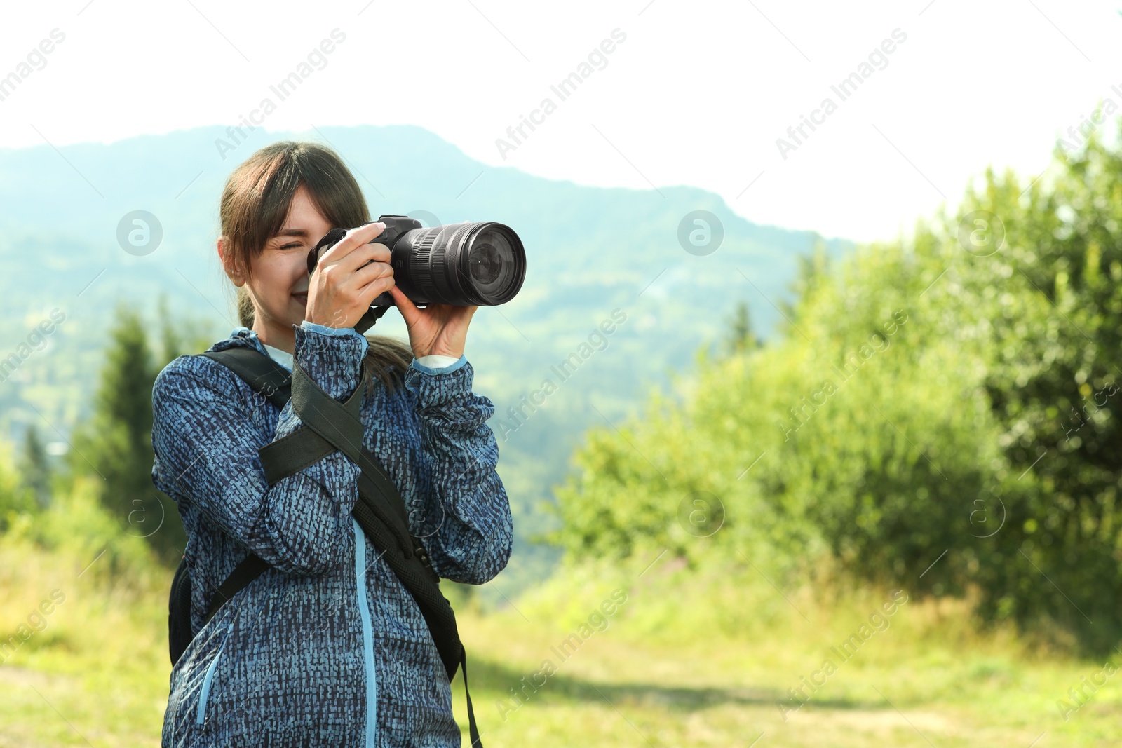 Photo of Photographer with backpack and camera taking picture of beautiful mountains. Space for text