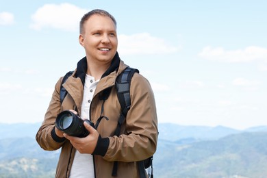 Photo of Photographer with backpack and camera in beautiful mountains. Space for text