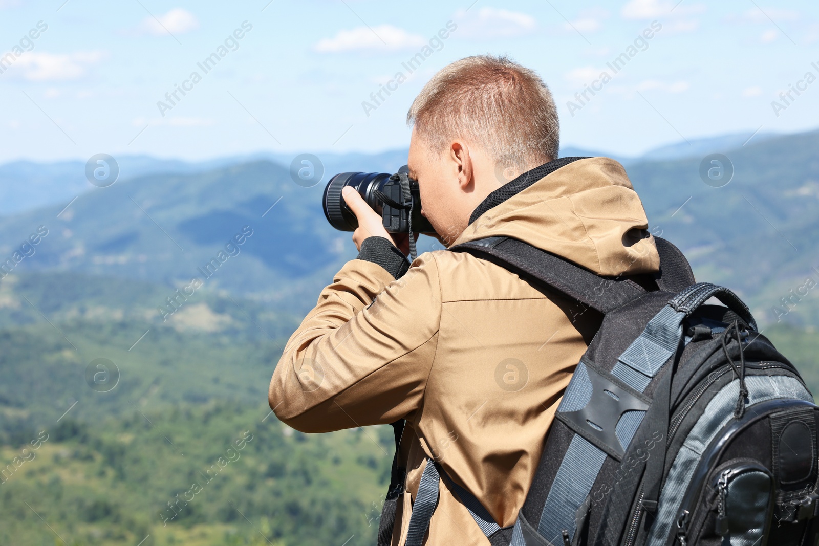 Photo of Photographer with backpack and camera taking picture of beautiful mountains