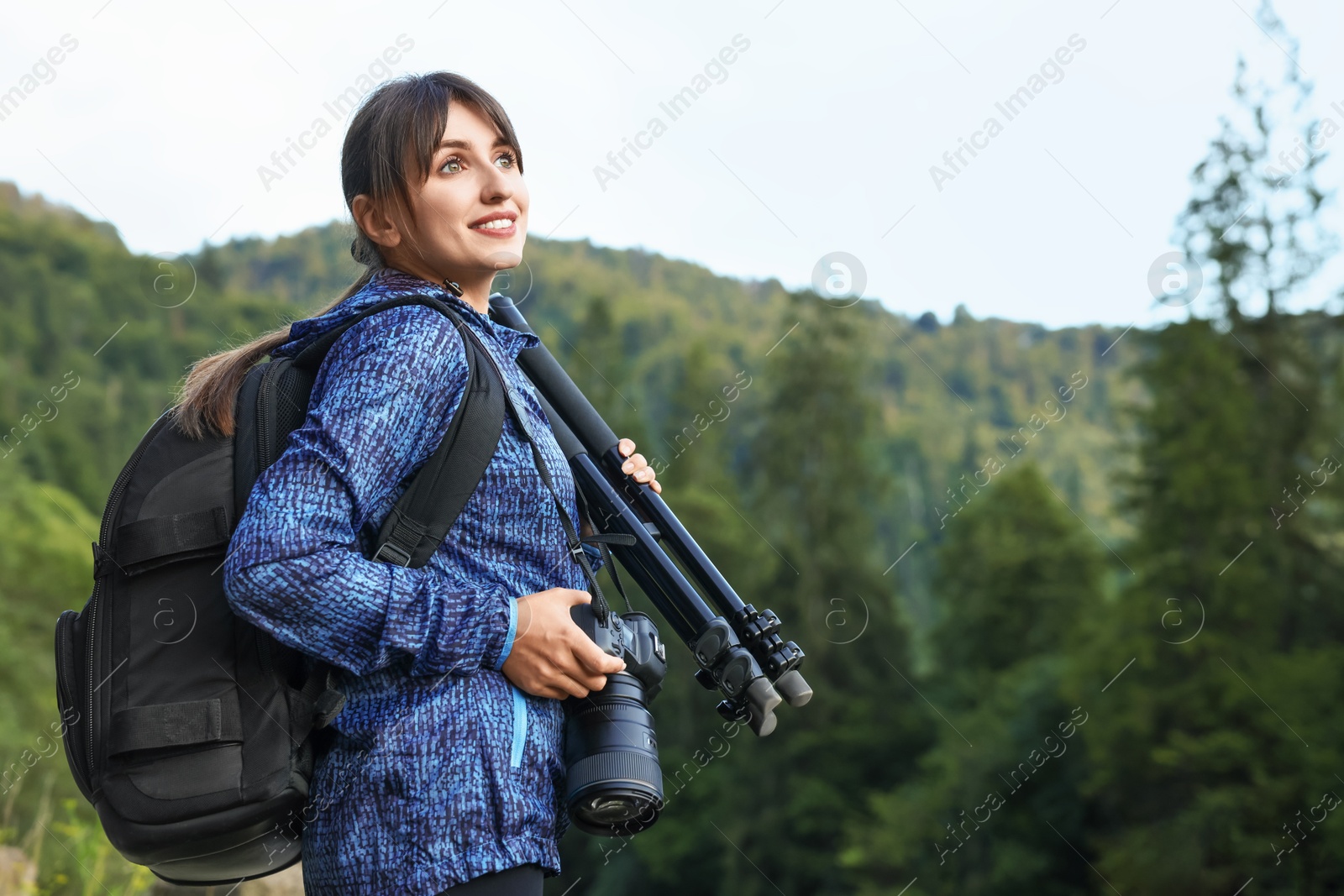 Photo of Photographer with backpack, camera and other professional equipment outdoors. Space for text