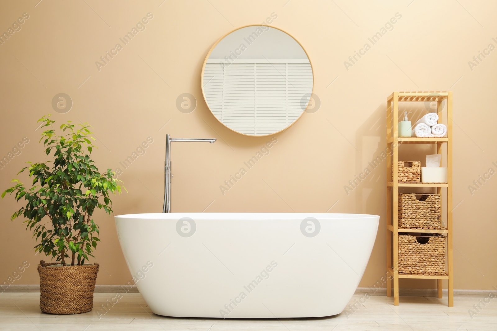 Photo of Bathtub, houseplant, shelving unit and mirror in stylish bathroom