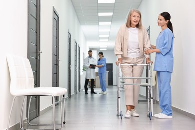 Nurse with senior woman in hospital hallway