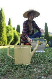 Woman with potted plant outdoors, focus on watering can