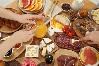 Photo of Women eating different food during brunch at wooden table, top view