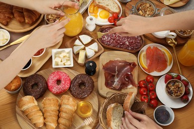 Photo of Women eating different food during brunch at wooden table, top view