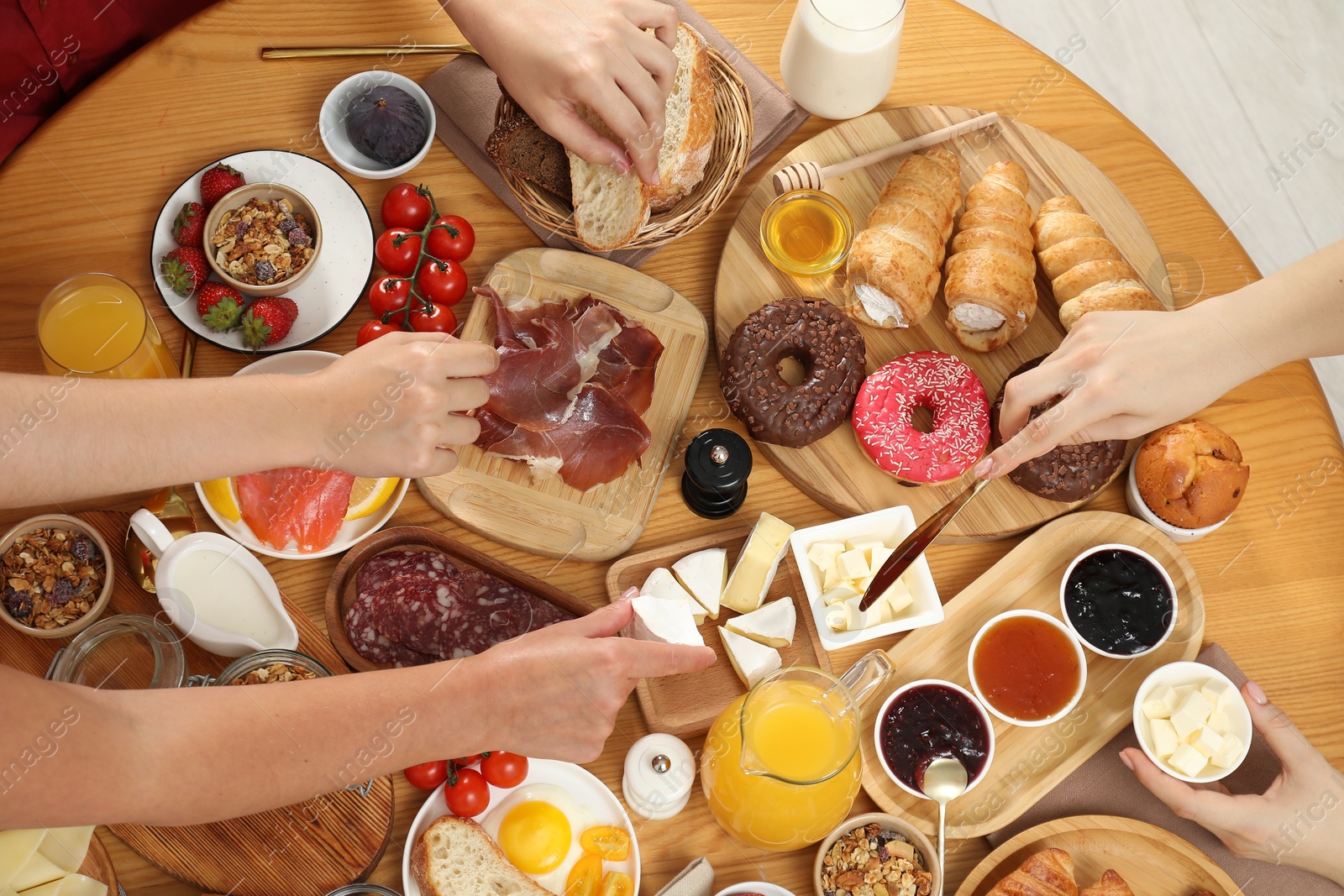 Photo of Women eating different food during brunch at wooden table, top view