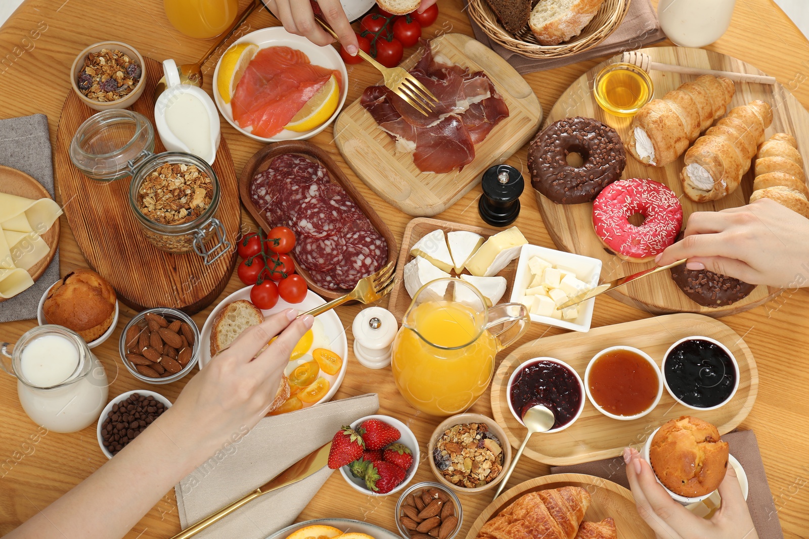 Photo of Women eating different food during brunch at wooden table, closeup