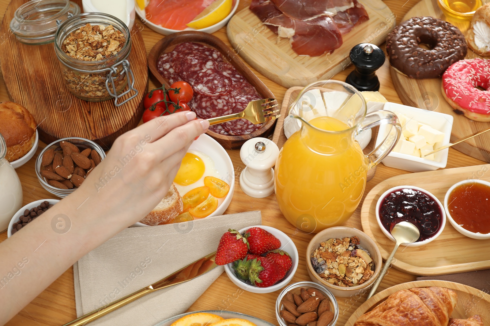 Photo of Woman eating different food during brunch at wooden table, above view