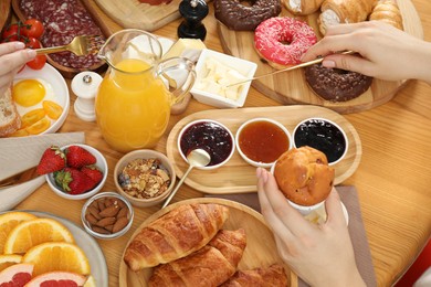 Photo of Women eating different food during brunch at wooden table, above view