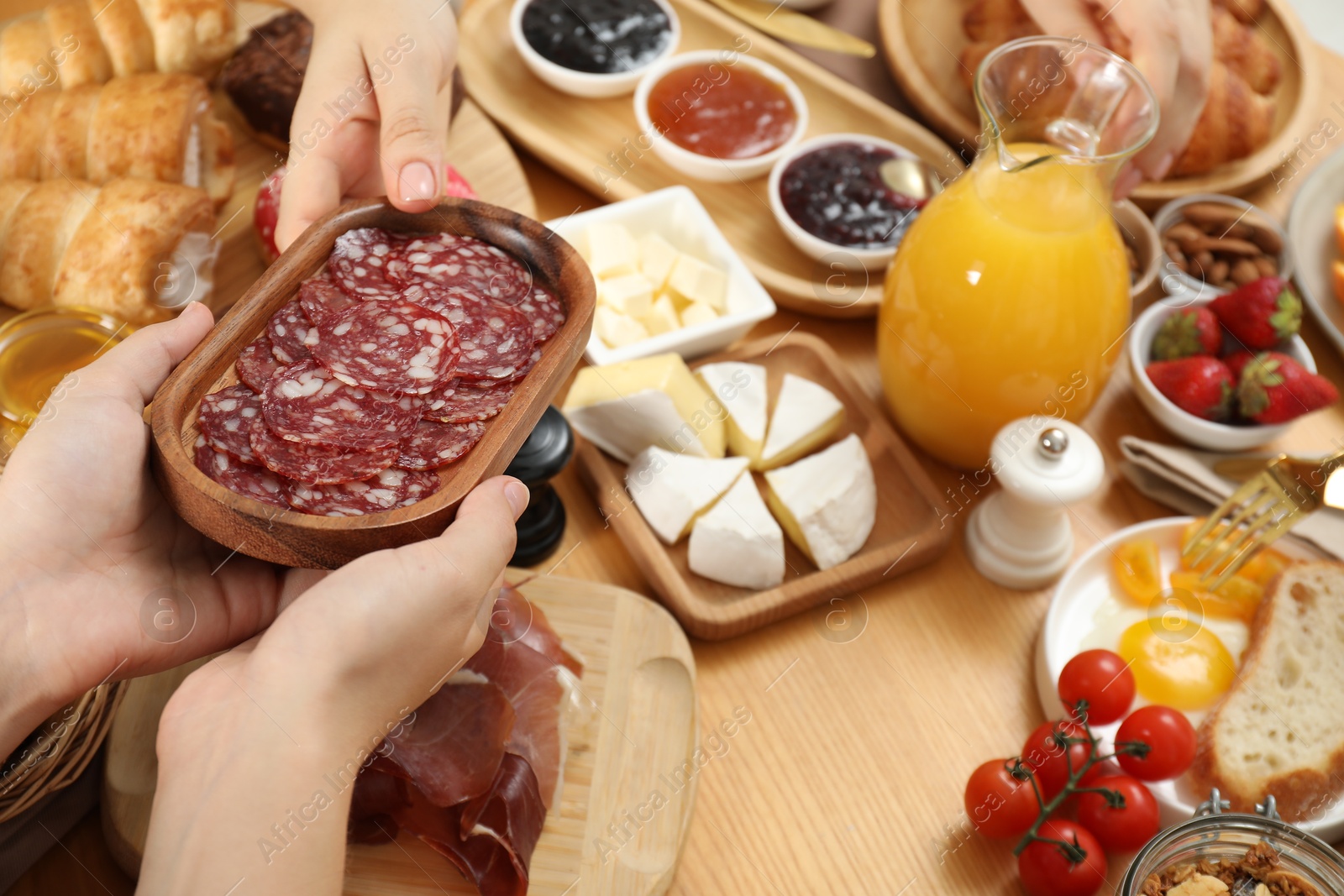 Photo of Women eating different food during brunch at wooden table, closeup