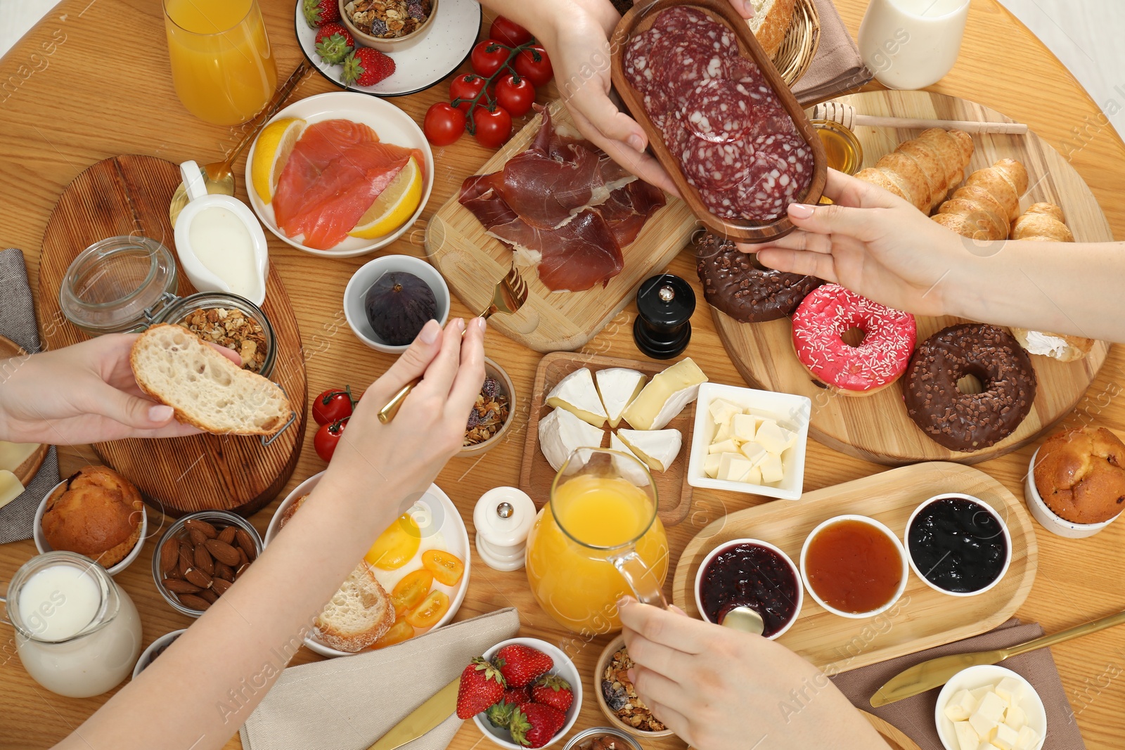 Photo of Women eating different food during brunch at wooden table, top view