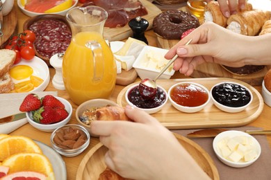 Photo of Woman eating different food during brunch at wooden table, closeup