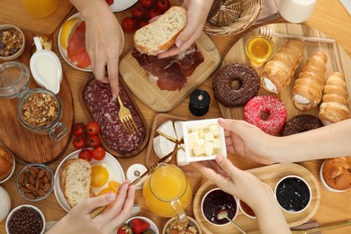 Photo of Women eating different food during brunch at wooden table, top view