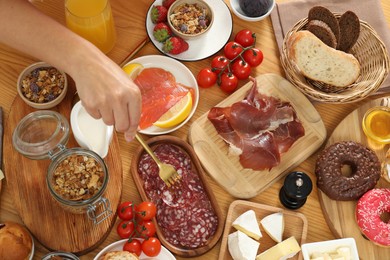 Photo of Woman eating different food during brunch at wooden table, top view