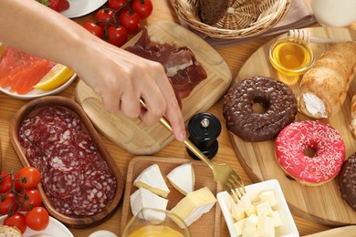 Photo of Woman eating different food during brunch at wooden table, top view