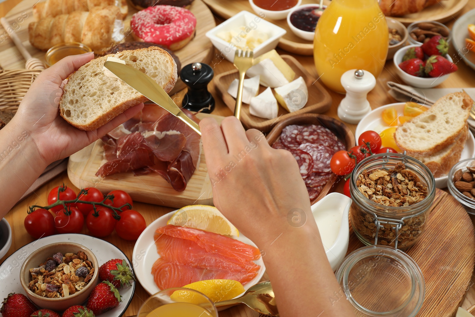 Photo of Woman eating different food during brunch at wooden table, closeup