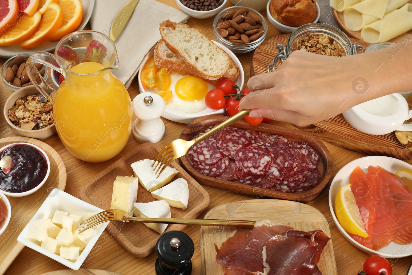 Photo of Woman eating different food during brunch at wooden table, closeup