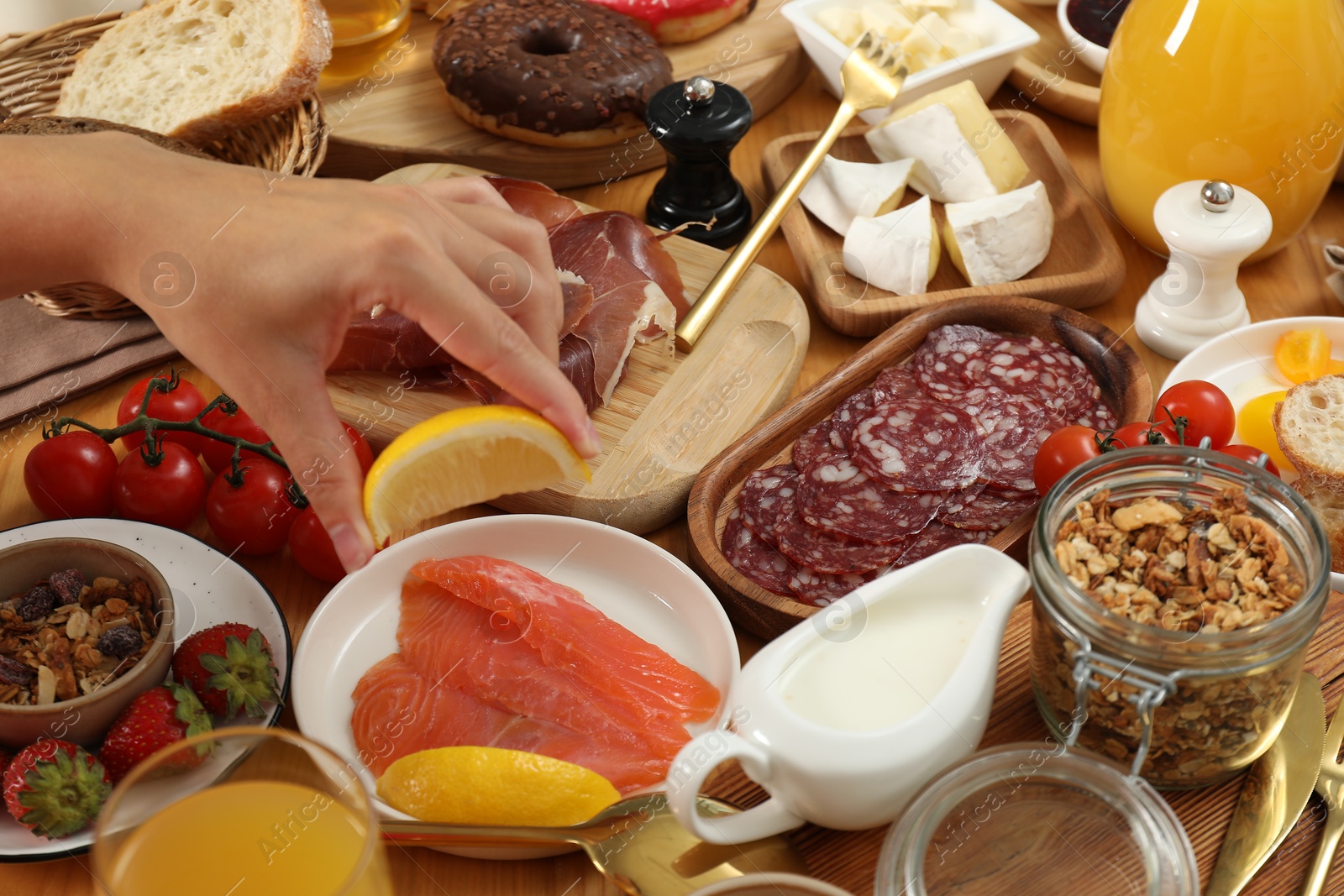 Photo of Woman eating different food during brunch at wooden table, closeup