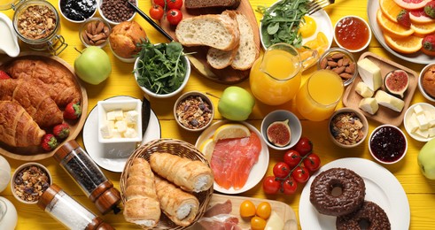 Photo of Different tasty food served for brunch on yellow wooden table, flat lay