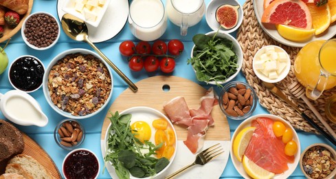 Photo of Different tasty food served for brunch on light blue wooden table, flat lay