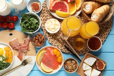 Photo of Different tasty food served for brunch on light blue wooden table, flat lay