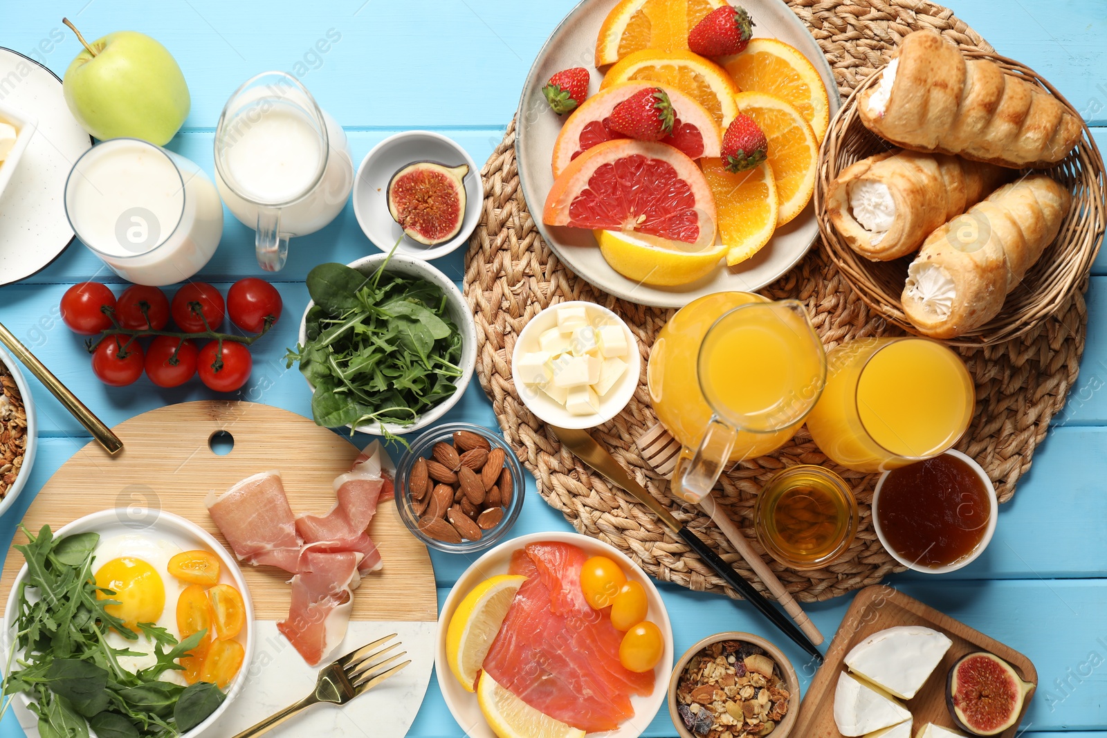 Photo of Different tasty food served for brunch on light blue wooden table, flat lay