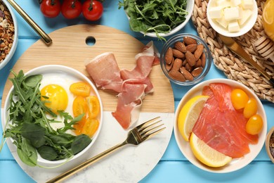 Photo of Different tasty food served for brunch on light blue wooden table, flat lay