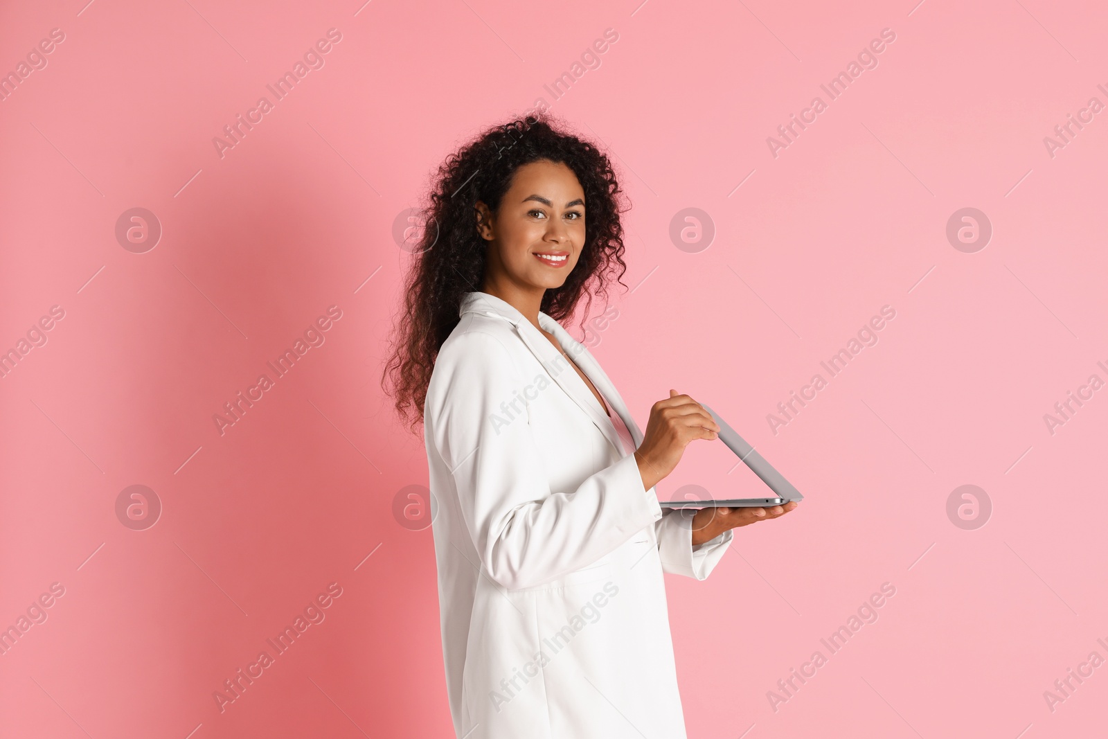 Photo of Beautiful woman in stylish jacket with laptop on pink background