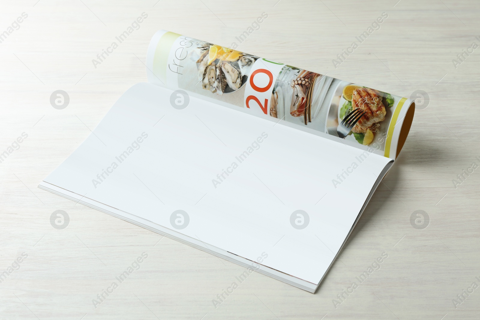 Photo of Open magazine on white wooden table. Mockup for design