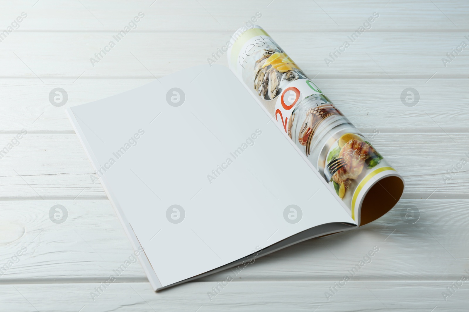 Photo of Open magazine with blank page on white wooden table. Mockup for design