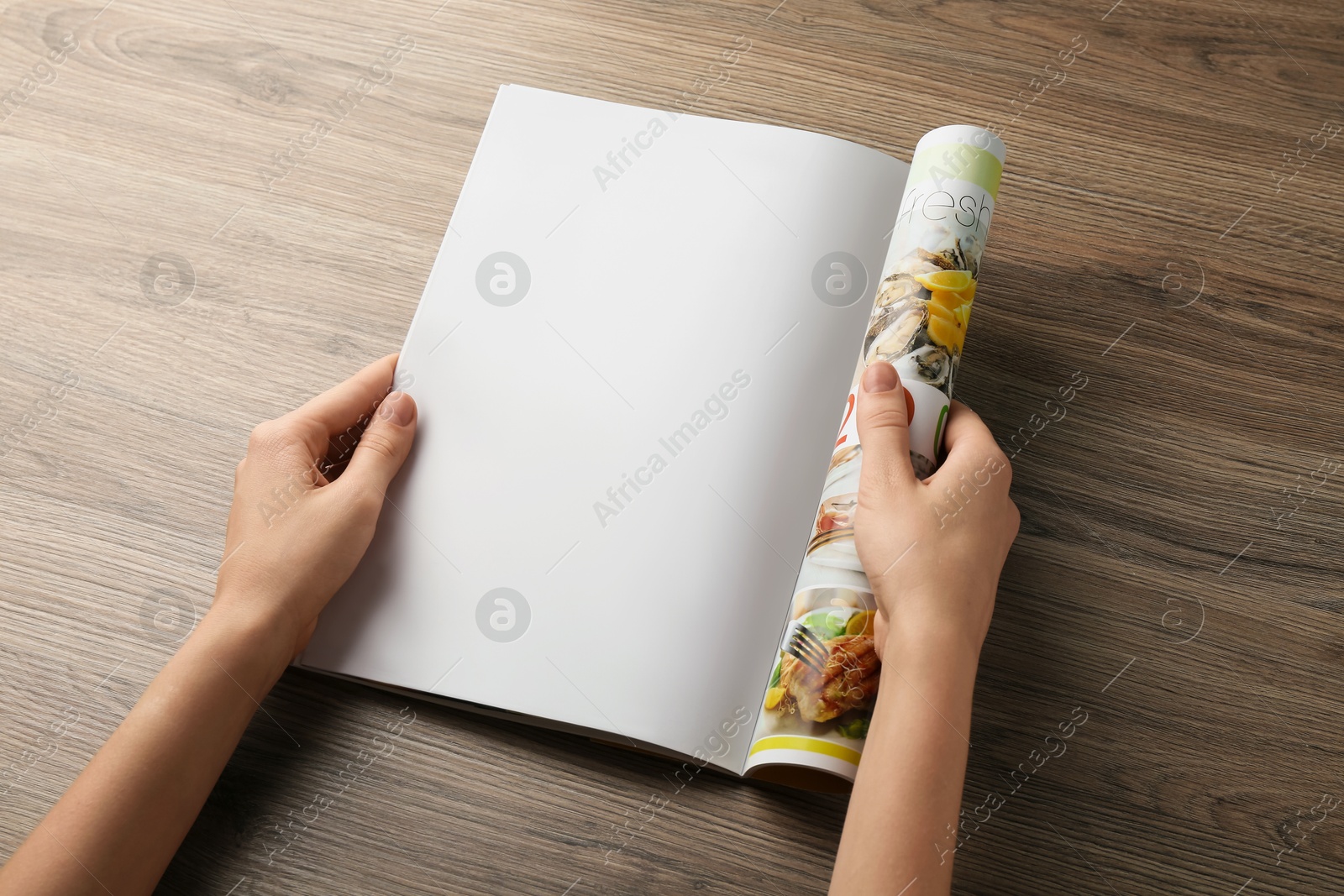 Photo of Woman reading magazine at wooden table, closeup. Mockup for design