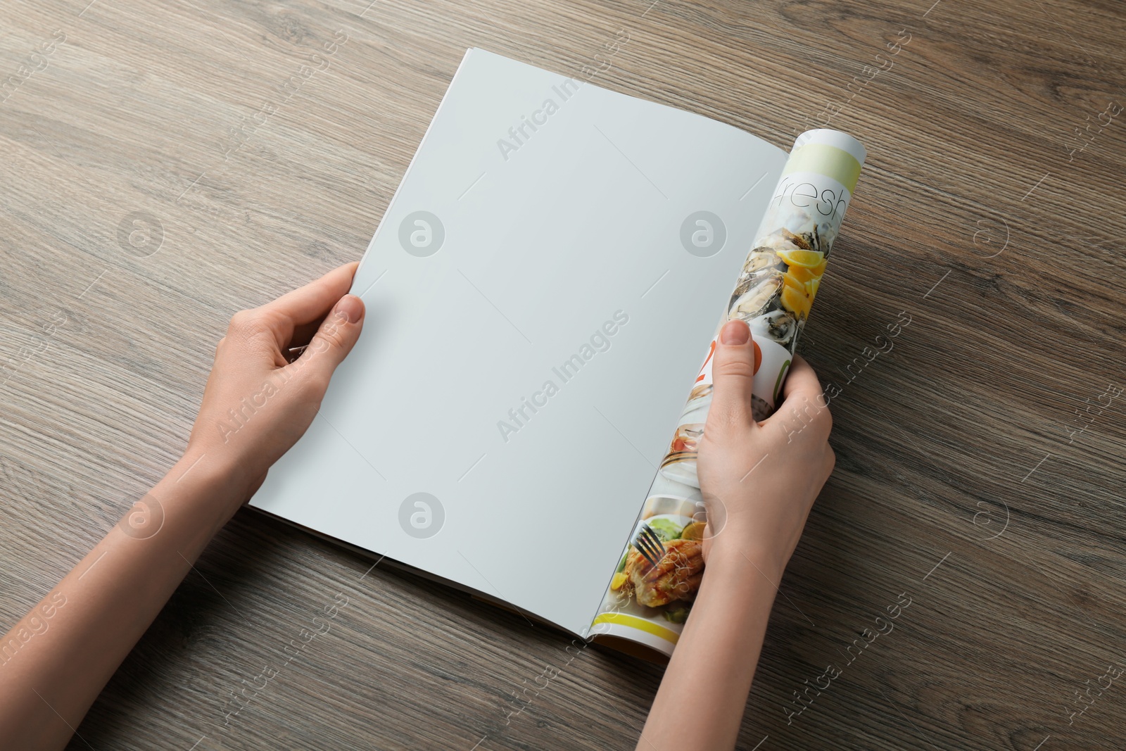 Photo of Woman reading magazine at wooden table, closeup. Mockup for design