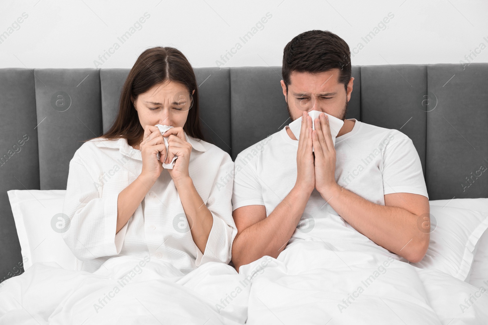 Photo of Cold symptom. Couple suffering from fever in bed at home