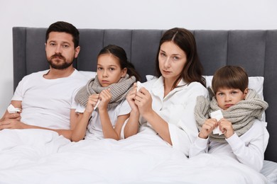 Cold symptom. Family suffering from fever in bed at home