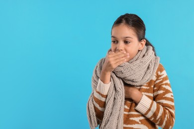 Cold symptom. Little girl suffering from fever on light blue background, space for text