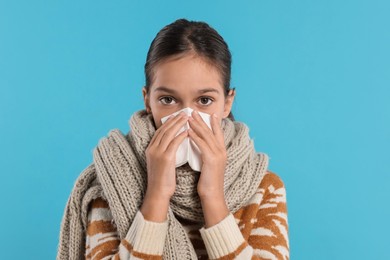 Cold symptom. Little girl with runny nose on light blue background