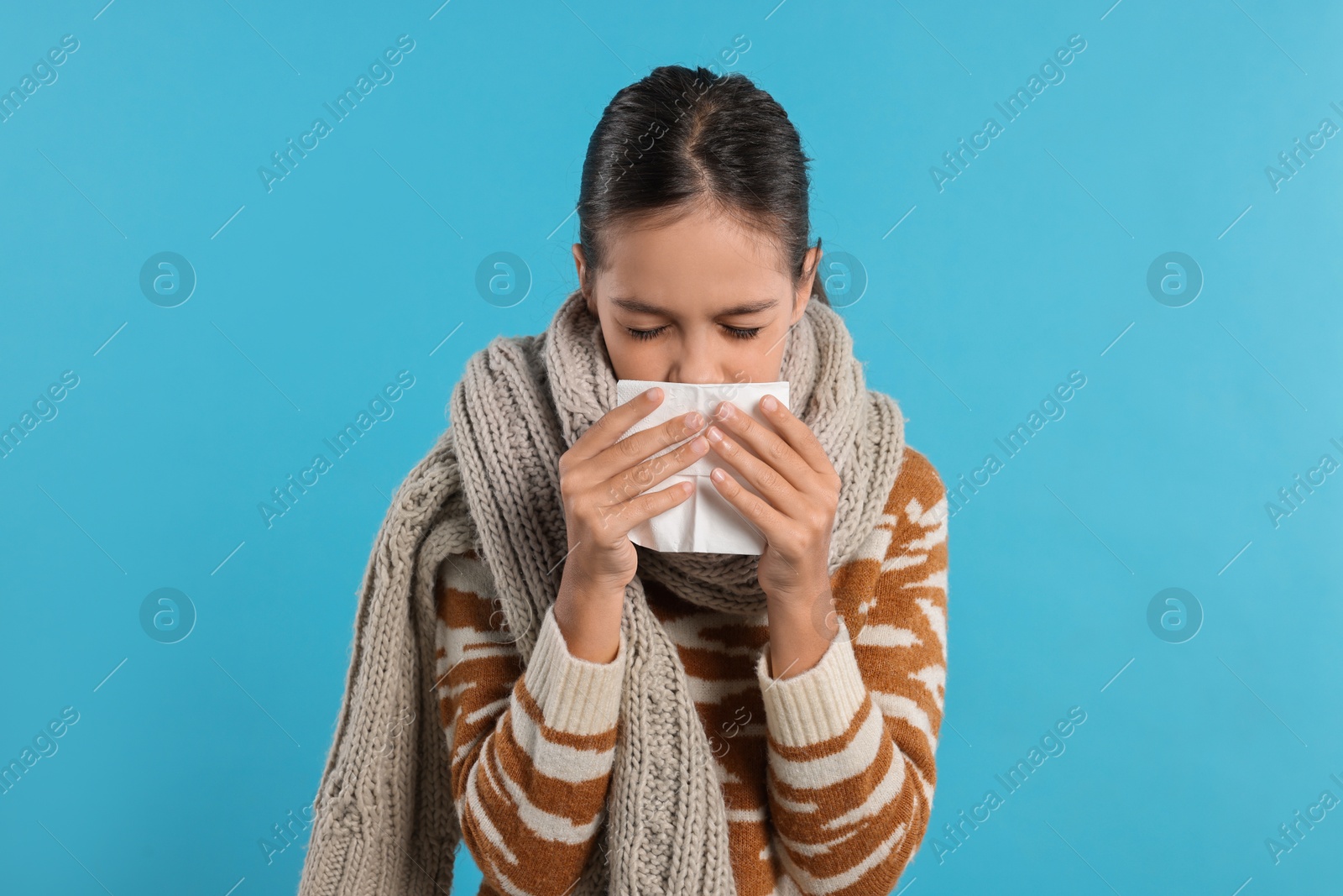 Photo of Cold symptom. Little girl with runny nose on light blue background