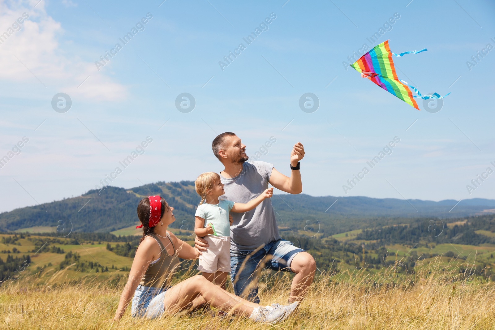 Photo of Happy family flying kite at field under blue sky