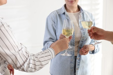 People clinking glasses of wine indoors, closeup