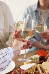 Photo of People clinking glasses of wine at served table, closeup